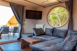 A cozy living area with a sofa, a coffee table, and a television mounted on the wall. - Mobile home with 2 bedrooms (Großenbrode)