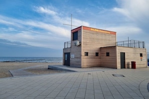 A small, two-story building with a sign reading 'DLAG Wasserrettung' near a beach. - Mobile home with 2 bedrooms (Großenbrode)
