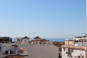 Ein Küstenwohngebiet mit Gebäuden, blauem Himmel und Blick auf das Meer.