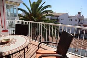Ein Balkon mit einem runden Tisch, einem Stuhl und einem Blumentopf.