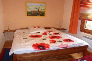 Ein Schlafzimmer mit einem hölzernen Bett, einem Gemälde an der Wand und einem Fenster mit Vorhängen.