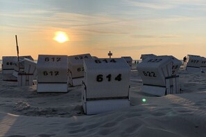 A row of numbered tombstones on a beach at sunset. - House on the sea dike (Hedwigenkoog)