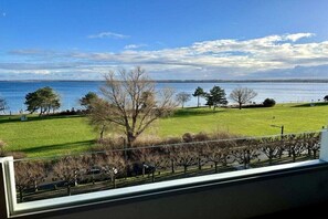 A view from a window overlooking a grassy area with trees and a body of water. - Holiday apartment with 1 bedroom (Lübeck-Travemünde)