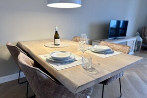 Een eethoek met een tafel gedekt voor twee personen, een fles wijn en een glas.