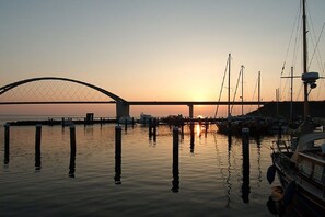 Ein Sonnenuntergang über ruhigem Wasser, im Hintergrund eine Brücke.