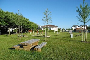 Ein Park mit Picknicktischen, einem Pavillon und Fitnessgeräten.