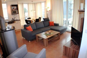 A modern living room with a sectional sofa, a coffee table, and a television. - Holiday apartment with 2 bedrooms (Großenbrode)