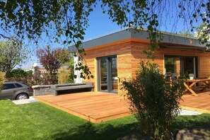 A modern house with a wooden exterior, a deck, and a car parked nearby. - Strandhaus Strandgut new 2017 (Großenbrode)