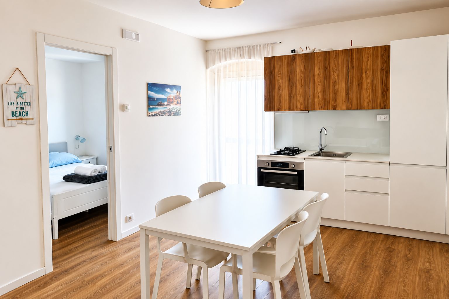 A compact hotel room with a bed, a small table, and a kitchenette.