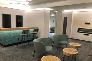 A reception area with a counter, two chairs, and a seating area with round tables. - Holiday apartment with 1 bedroom (Wismar)