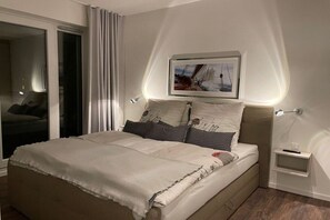 A bedroom with a bed, a nightstand, a framed picture above the bed, and a sliding glass door. - Holiday apartment with 1 bedroom (Wismar)