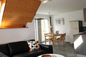 Ein stilvoller Wohnraum mit schwarzem Sofa, einem Esstisch und einer Küchenzeile.