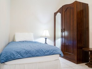 A bedroom with a bed, a nightstand, a lamp, and a wooden wardrobe. - Mango Overboard Garden Retreat in the Heart of the South Coast (Bridgetown)