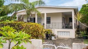 Un bâtiment à deux étages doté d’un balcon, entouré de plantes tropicales.