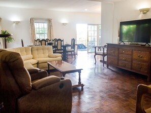 Una sala de estar con sofá, sillón, mesa de centro, televisor y aparador.