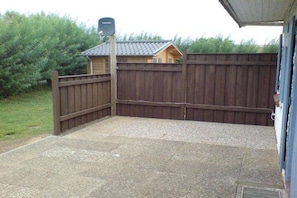 A fenced backyard with a gravel patio and a wooden fence. - "Margarete Leiblein" (Nordstrand)
