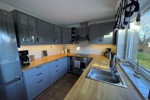 Eine moderne Küche mit grauen Schränken, einer Edelstahlspüle und einem Fenster mit Vorhängen.