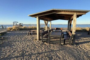 Ein Strand mit einem hölzernen Pavillon, Bänken und einem Tisch.