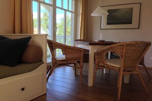 A room with a sofa, two wicker chairs, a table, a lamp, and a framed picture on the wall. - Holiday apartment with 2 bedrooms (Graal Müritz)