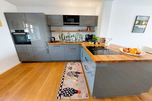 A modern kitchen with grey cabinets, a wooden countertop, and a built-in stove. - Holiday home with 2 bedrooms (Brodersby-Goltoft)