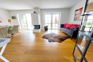A spacious living area with a fireplace, a sofa with red cushions, and a glass coffee table. - Holiday home with 2 bedrooms (Brodersby-Goltoft)