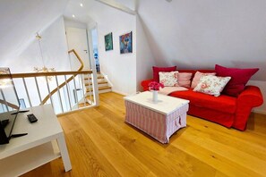 A living room with a red sofa, a white coffee table, and a staircase. - Holiday home with 2 bedrooms (Brodersby-Goltoft)