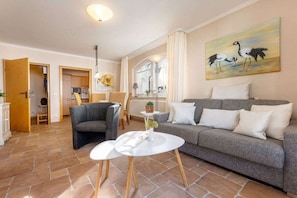 A living room with a grey sofa, a white coffee table, and a painting of birds on the wall. - ""La Gaviota"" in Villa Gudrun (Binz)