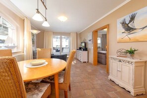 A dining area with a round table, chairs, and a cabinet with decorative items. - ""La Gaviota"" in Villa Gudrun (Binz)
