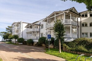 En byggnad med flera våningar och balkonger, en parkeringsskylt och en asfalterad uppfart.