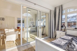 Una camera da letto con un letto, una scrivania, una sedia e una porta-finestra che dà su un balcone.