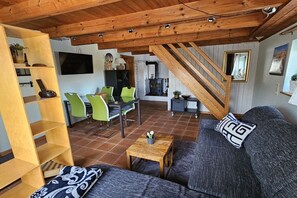 A living room with a sofa, a wooden coffee table, and a TV mounted on the wall. - Holiday apartment with 1 bedroom (Hattstedt)