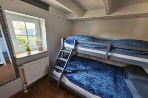 A bunk bed room with a window, a radiator, and a small table with a plant. - Holiday apartment with 1 bedroom (Hattstedt)
