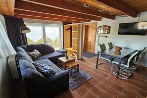 A cozy living room with a sofa, coffee table, and a dining area with chairs and a table. - Holiday apartment with 1 bedroom (Hattstedt)