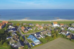 An aerial view of a coastal residential area with houses, a beach, and a pier. - Holiday home with 3 bedrooms (Schönberg)