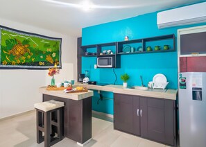 Cozinha moderna com parede azul de destaque, micro-ondas, geladeira e uma pequena ilha com pia.