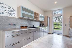 A modern kitchen with a built-in espresso machine, a coffee maker, and a large window providing a view of the outdoors. - Seeperle Karlshagen with whirlpool (Karlshagen)