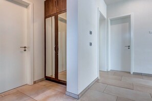 Un couloir avec une armoire en bois, une porte blanche et un sol carrelé.