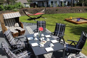 An outdoor seating area with a table set for two, surrounded by chairs with striped cushions. - Seeperle Karlshagen with whirlpool (Karlshagen)