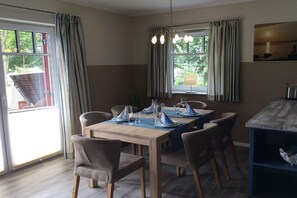 Ein Essbereich mit einem Tisch für vier Personen, Stühlen, einer Hängeleuchte und Blick durch das Fenster.