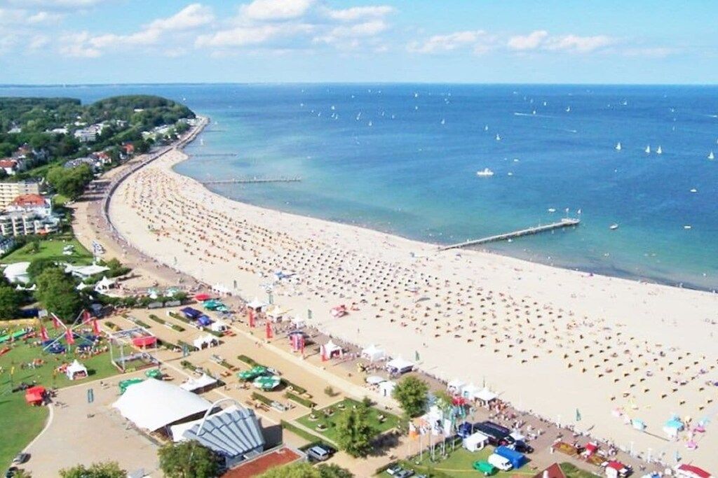 A beach with a long stretch of sand and a pier extending into the water.