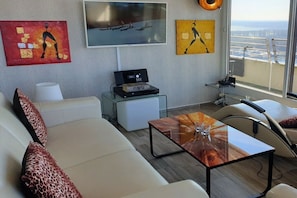 Ein modernes Wohnzimmer mit einer Couch, Sesseln, einem Couchtisch und Kunstwerken an den Wänden.