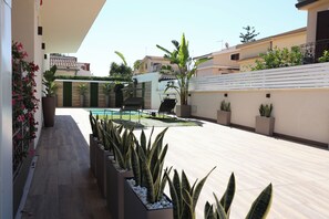 Eine Dachterrasse mit Pool, Blumentöpfen und Gartenmöbeln.