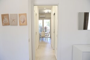 Een gang die uitkomt in een eetgedeelte met een tafel en stoelen, en drie kunstwerken aan de muur.