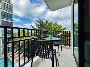 A balcony with a table and chairs, a potted plant, and a view of a swimming pool and buildings. - 1-Bedroom Condo for Rent at Mira Monte, Soi Hua Hin 94 (Tambon Hua Hin)