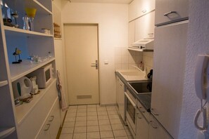 A compact kitchen with a microwave, stove, and sink. There is a door leading to another room. - Holiday apartment with 1 bedroom (Schönberger Strand)