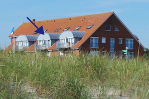 A red-roofed building with multiple windows and a flag. - Holiday apartment with 1 bedroom (Schönberger Strand)