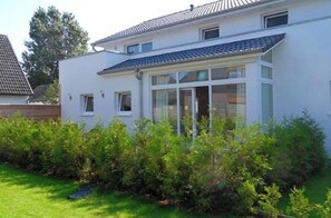 A two-story house with a covered porch, surrounded by a well-maintained hedge. - Holiday apartment with 2 bedrooms (Schönberg-Kalifornien)