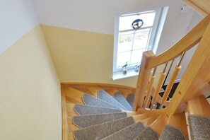 Eine Holztreppe mit Teppichstufen, die zu einer Zwischenebene führt.