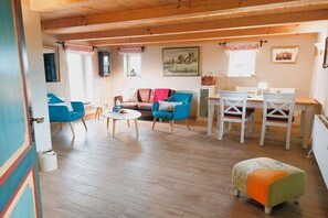 A cozy living room with a sofa, chairs, a coffee table, and a dining area with a table and chairs. - Holiday home with 2 bedrooms (Steinbergkirche)