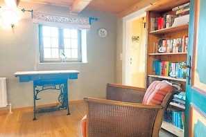 A room with a wooden desk, wicker chairs, a bookshelf, and a window with a curtain. - Holiday home with 2 bedrooms (Steinbergkirche)
